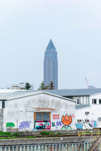 Deutschland, Hessen, Frankfurt, der Messturm hinter einer Gewerbehalle am Main. Deutschland, Hessen, Frankfurt, der Messturm hinter einer Gewerbehalle am Main.